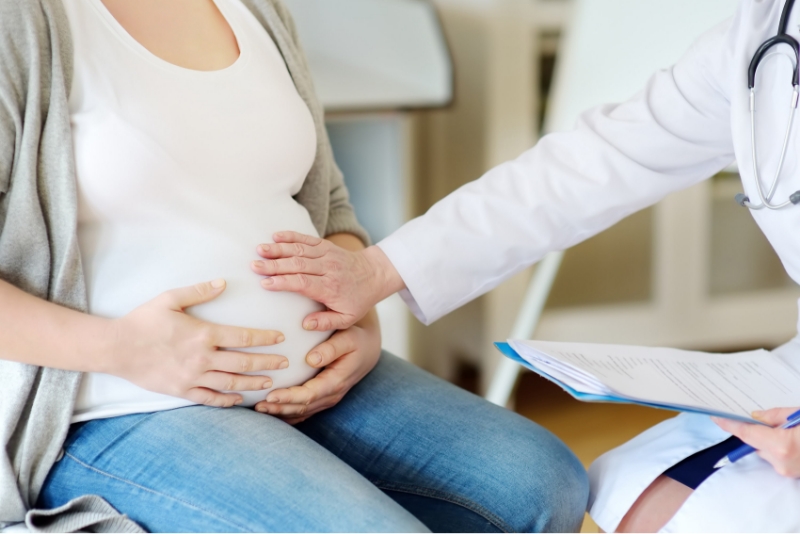 Femme enceinte assise qui se tient le ventre