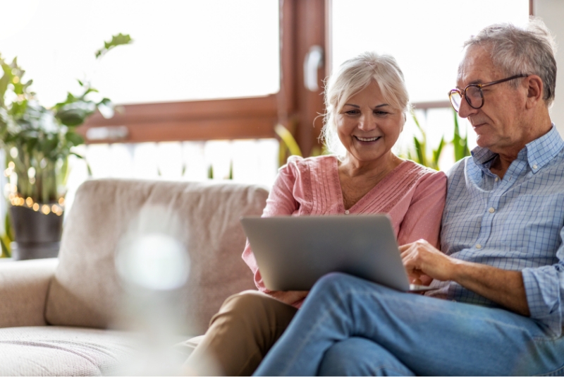 Couple senior souriant devant un ordinateur