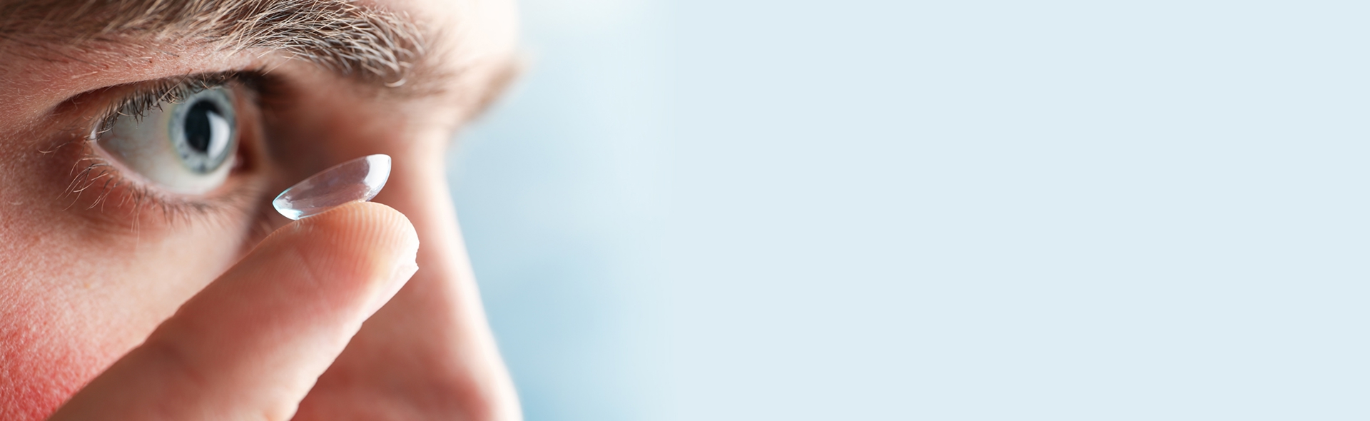 Homme aux yeux bleus mettant une lentille de contact