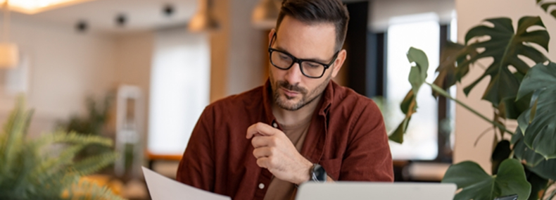 homme_lunettes_document_et_ordinateur