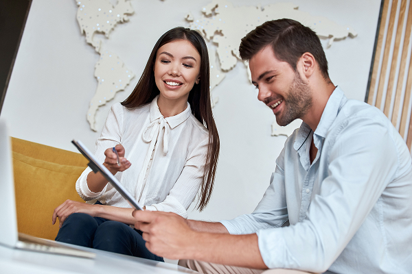 Image d'une employée souriante dans un office de tourisme qui conseille un client