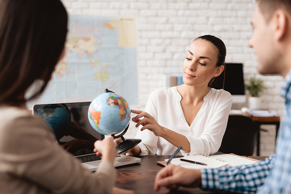 Image d'une employée qui conseille un couple de voyageurs dans un office de tourisme