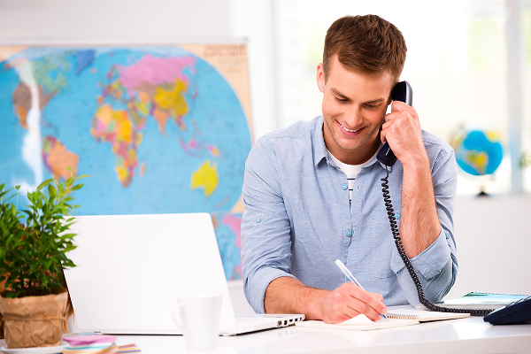 Image d'un conseiller en office de tourisme au téléphone et devant son ordinateur
