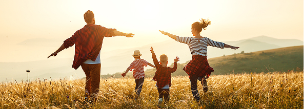 famille heureuse qui cours dans les champs sous le soleil couchant