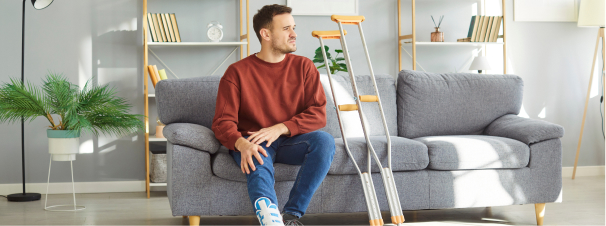 homme blesse sur son canape en arrte de travail couvert par la mutuelle d'entreprise