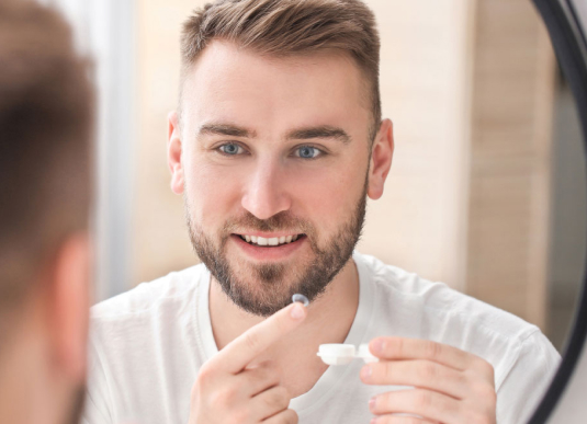 homme devant un miroir mettant une lentille de contact